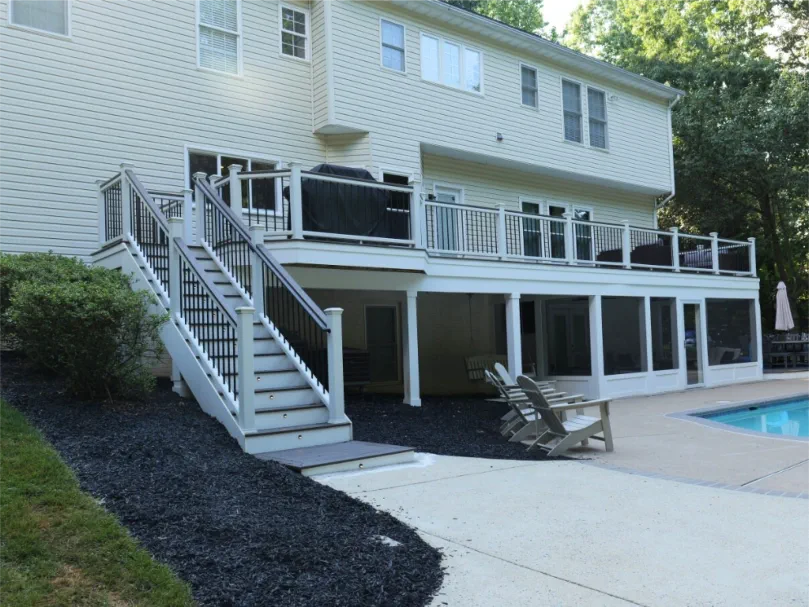 Custom outdoor deck with composite decking, modern railing, and built-in lighting in a professionally landscaped backyard.